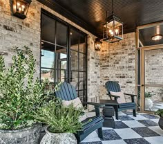 two chairs sitting on top of a black and white checkered floor next to potted plants