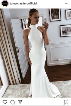 a woman in a white dress taking a selfie