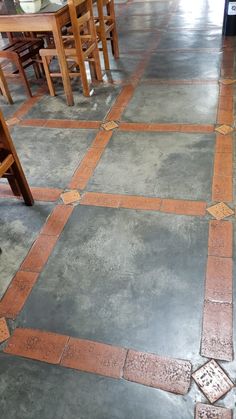 the floor is made out of cement and has orange tiles on it, along with wooden chairs