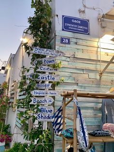 several street signs are posted on the side of a building with plants growing up against it