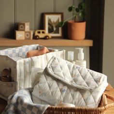 a basket filled with baby items sitting on top of a wooden table next to a potted plant