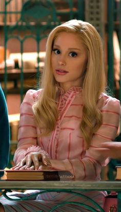 a woman sitting at a table with a book in her hand