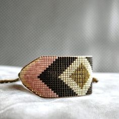 a beaded bracelet on a bed with a white sheet in the background and a gray wall behind it