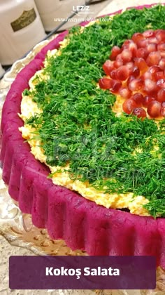 a cake decorated with green grass and red grapes