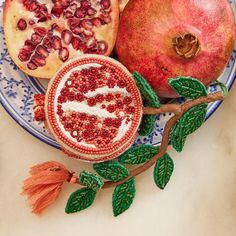 two pomegranates on a blue and white plate next to some leaves