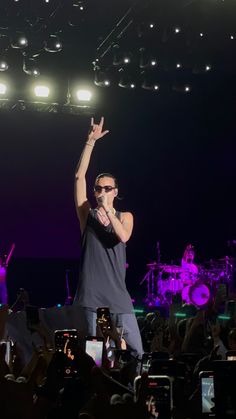 a man standing on top of a stage with his arms in the air and hands up