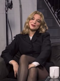 a woman sitting on top of a couch next to a cup