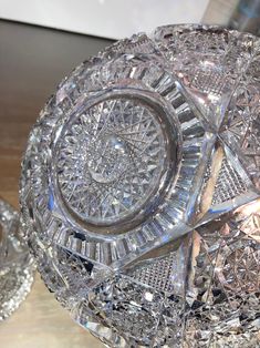 a glass bowl sitting on top of a wooden table next to other crystal dishes and bowls