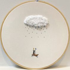 there is a embroidery on the wall that has a cloud and a boat in it