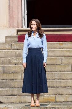 a woman standing in front of some steps wearing a blue shirt and black midiskit