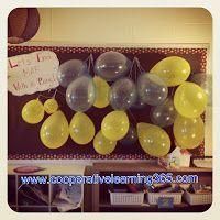 balloons are hanging from the ceiling in front of a bulletin board