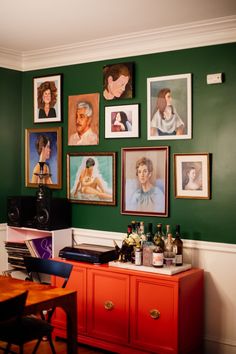 a room with pictures on the wall and an orange cabinet in front of it,