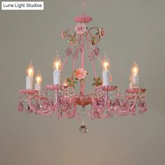 a pink chandelier hanging from the ceiling with five candles in front of it