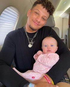 a man holding a baby in his arms while sitting on the back of an airplane