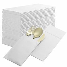 a stack of white napkins with gold forks and knives next to eachother