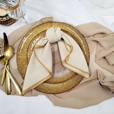 a table setting with gold and white plates, silverware and napkins on it