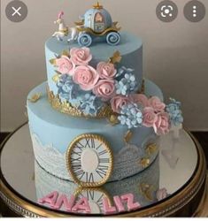 there is a blue cake with pink flowers on the top and gold trimmings