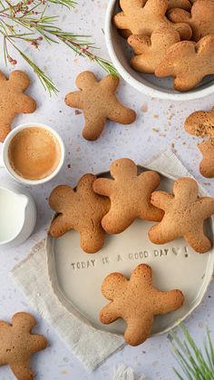 some cookies are sitting on a plate next to two mugs and one is empty