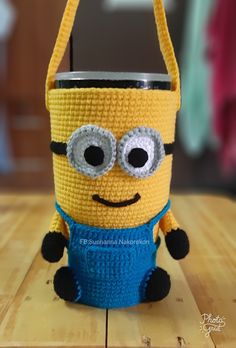 a crocheted yellow and blue minion holding a cell phone in it's hand