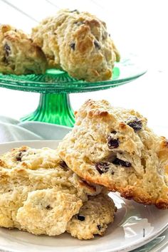 three scones sitting on top of a white plate next to a green cake stand