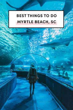 a woman is walking through an aquarium with sharks in the background and text overlay reads best things to do in my little beach, sc