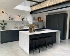 a kitchen with black cabinets and white marble counter tops, an island in the middle