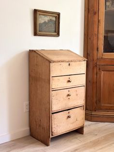 an old wooden chest of drawers next to a painting on the wall in a room