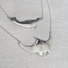 two silver necklaces with dolphins on them