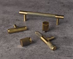 four brass knobs and two small cylindrical knobs on a gray surface with grey background