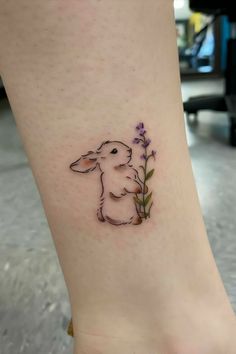 a small tattoo on the ankle of a woman's leg with a rabbit and flowers