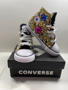 "Designing your own converse with pearls, rhinestones is a creative way to express your individual style. With a wide range of colors, shapes, and sizes available, you can create a truly unique look that reflects your personality. Start by deciding on your color palette and design theme. Using a combination of different sizes of pearls and stones to create an eye-catching pattern and delicate satin ribbons to provide a luxurious touch to your one-of-a-kind shoes for a special occasion that will Converse With Pearls, Rainbow Converse, Custom Converse Shoes, Converse Gold, Bedazzled Shoes, Boys Converse, Bling Converse, Baby Bling, Custom Converse