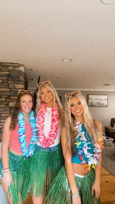 three women in hula skirts posing for the camera