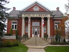 an old brick building with columns and flags on it's front porch, sitting in the grass