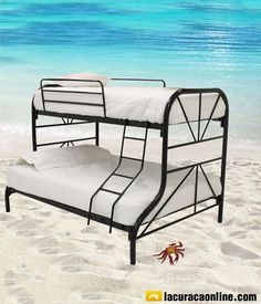 two bunk beds sitting on top of a sandy beach next to the ocean and blue water