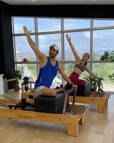 two people doing pivots in front of a large window while sitting on exercise equipment