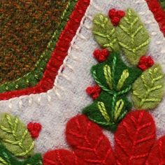 a close up view of an ornament with red flowers and green leaves on it