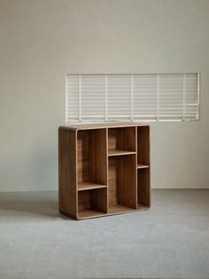 a wooden shelf sitting on top of a carpeted floor next to a white wall