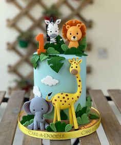 a blue cake with animals and plants on it sitting on top of a wooden table