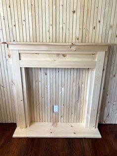 an empty fireplace with wood paneling on the wall