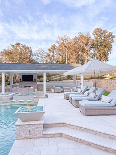 an outdoor pool with lounge chairs and umbrellas