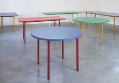 several tables in different colors and sizes are arranged on the floor, with one table standing out from the others