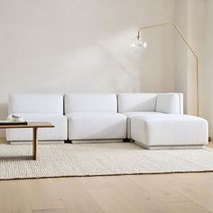 a white couch sitting on top of a wooden floor in a living room next to a table