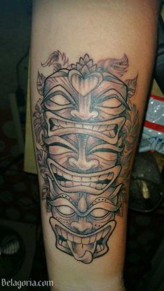 a tattoo on the leg of a man with a mask and flowers in his hair