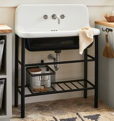 a white sink sitting on top of a wooden shelf next to a counter topped with dishes