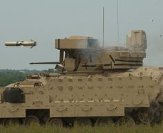 an army tank is in the middle of a grassy field with a plane flying over it