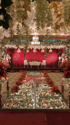 a room filled with lots of tables covered in flowers and greenery next to a chandelier