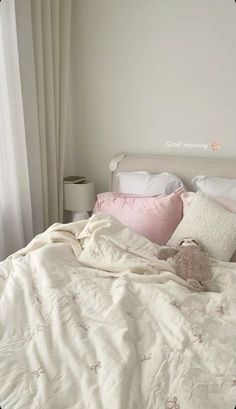 an unmade bed with white sheets and pink pillows