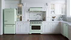 a kitchen with white cabinets and green appliances in the center, along with wood floors