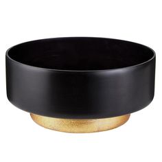 a black bowl sitting on top of a white table next to a gold plated object