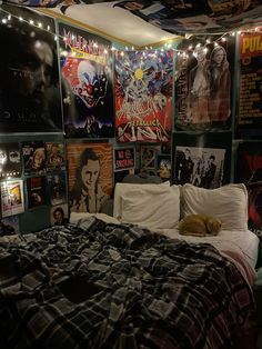 a bedroom with posters on the wall and a cat laying on the bed in front of it